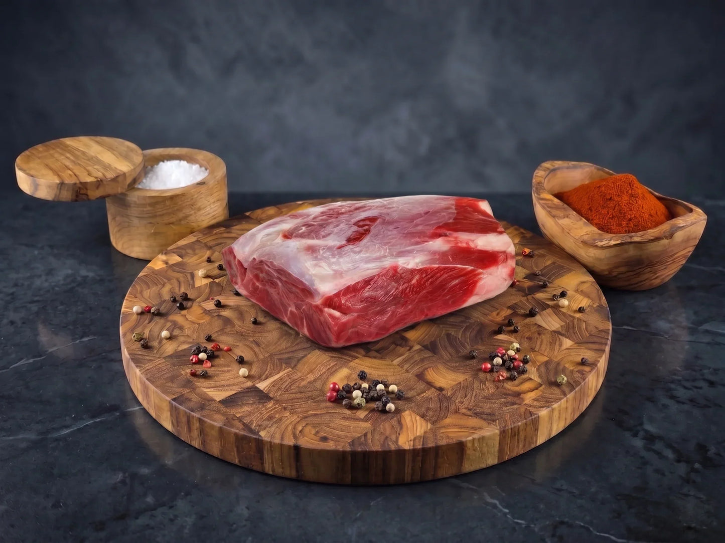 Raw steak on a wooden cutting board with salt, pepper, and spices on a dark background