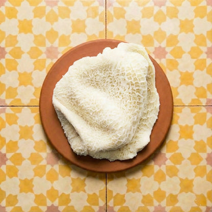 White honeycomb tripe on a brown earthenware plate against a background of yellow and white geometric Moroccan Zellige tiles