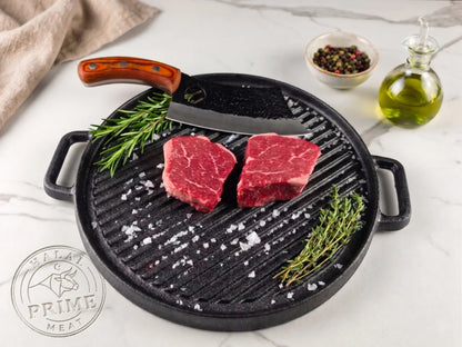 Two raw steaks on a cast iron grill pan with herbs and salt, on a light background.