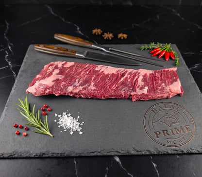 skirt steak on a slate board with spices and a knife.