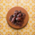 Photograph of glistening dark red meat on a rustic terracotta plate set against a vibrant yellow and white geometric Moroccan zellige tile background