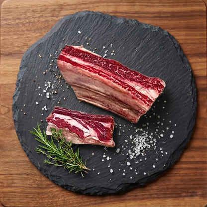 Beef Chuck ribs on a slate board with salt and rosemary