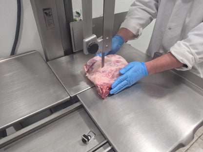 butcher cutting a slab of lamb to make lamb chuck
