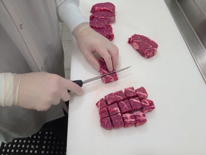 Butcher cutting pieces of tender beef stew